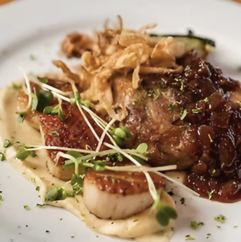 Seared Maine scallops and bacon over creamed corn, plated with microgreens and crispy shallots, at The Noble Lion in Victoria, Minnesota