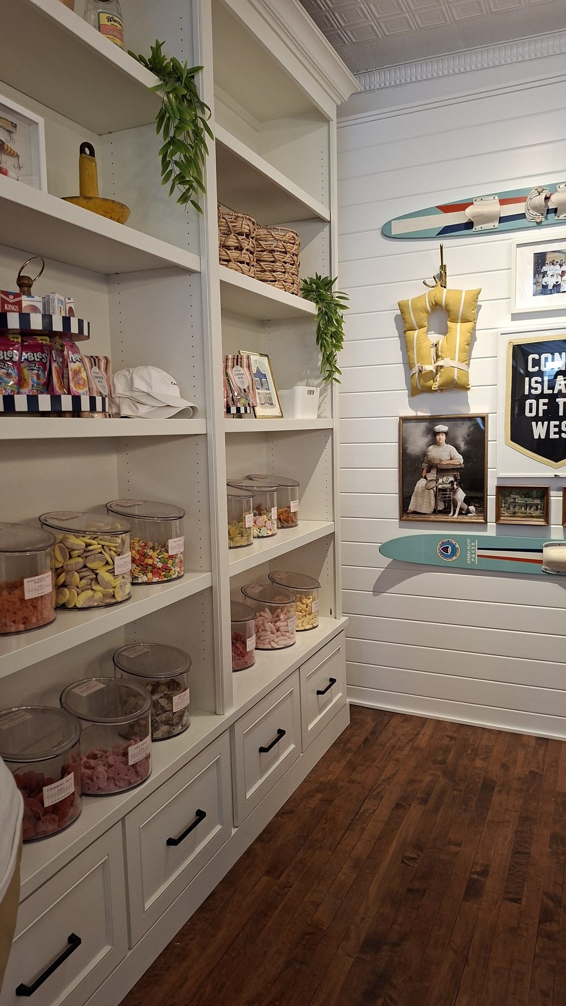 Inside Coney's candy shop in Waconia: white shelves of bulk candy jars beside a wall with vintage water skis and a Coney Island of the West pennant