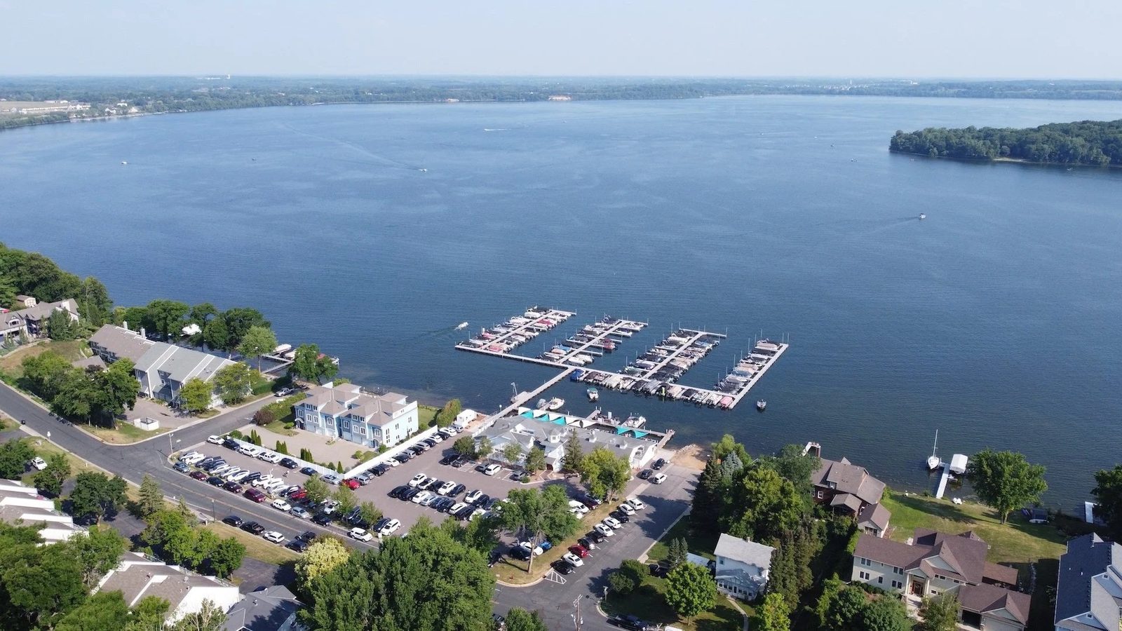 Aerial view of Lola's Lakehouse on the Waconia shore, with its marina piers reaching into Lake Waconia and Lake Street curving along the water