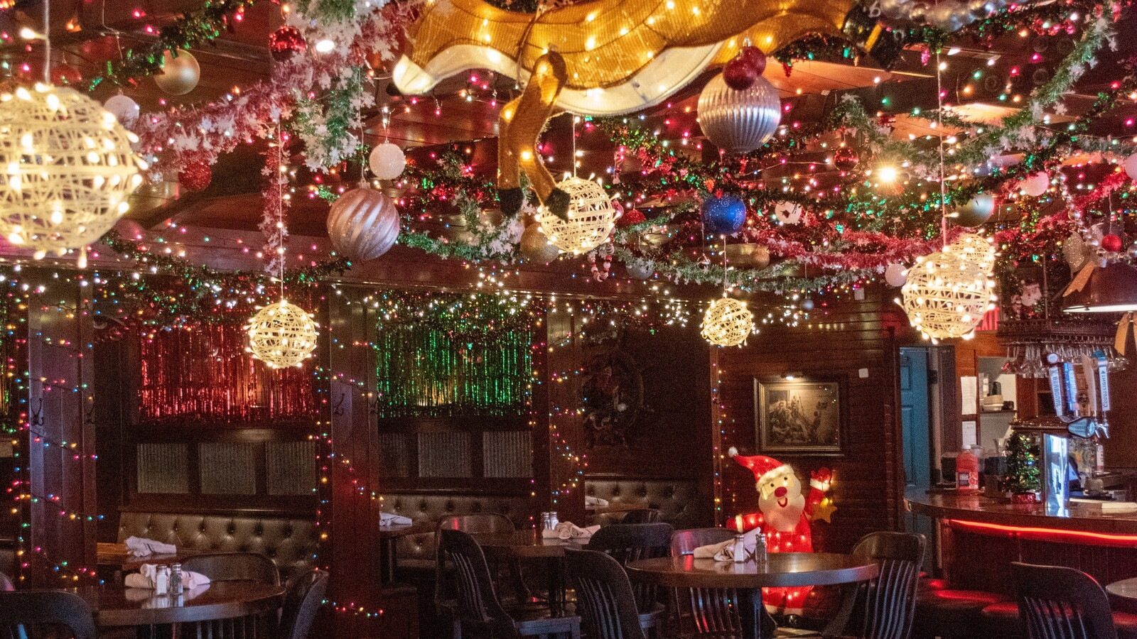 Lola's Jingle Bar in Waconia, a dining room ceiling packed with garland, tinsel, giant ornaments and glowing light balls above booths and tables