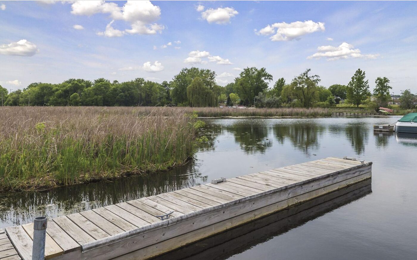 The no-wake channel south out of Lost Lake toward Cooks Bay, lined with cattails and reeds, with boats moored at the dock