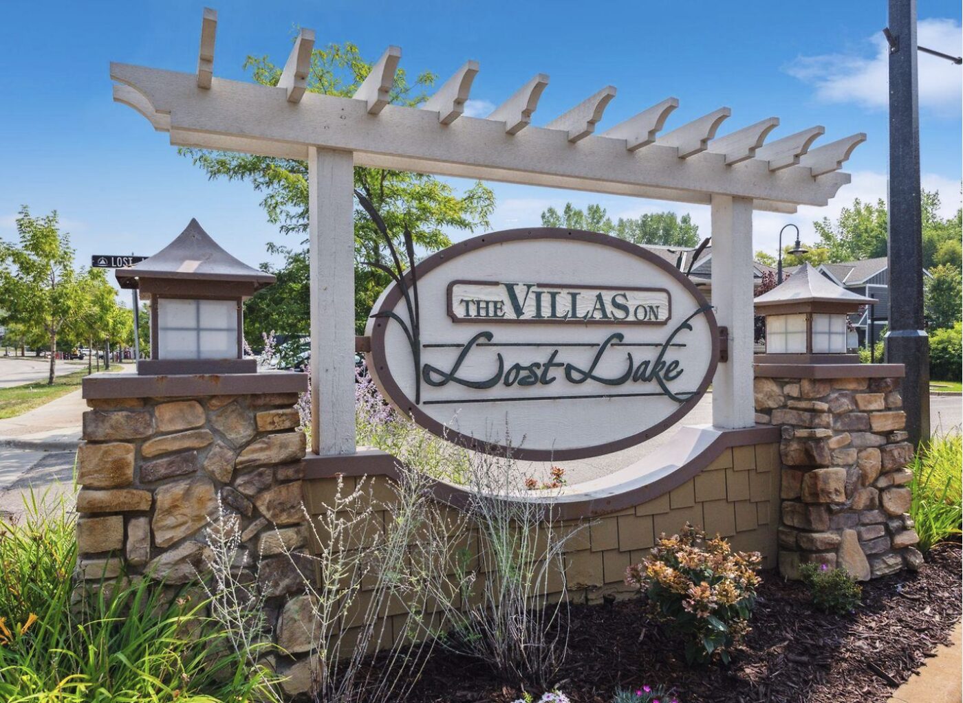 The Villas on Lost Lake entrance sign and landscaped pergola overlooking the water in Mound, Minnesota