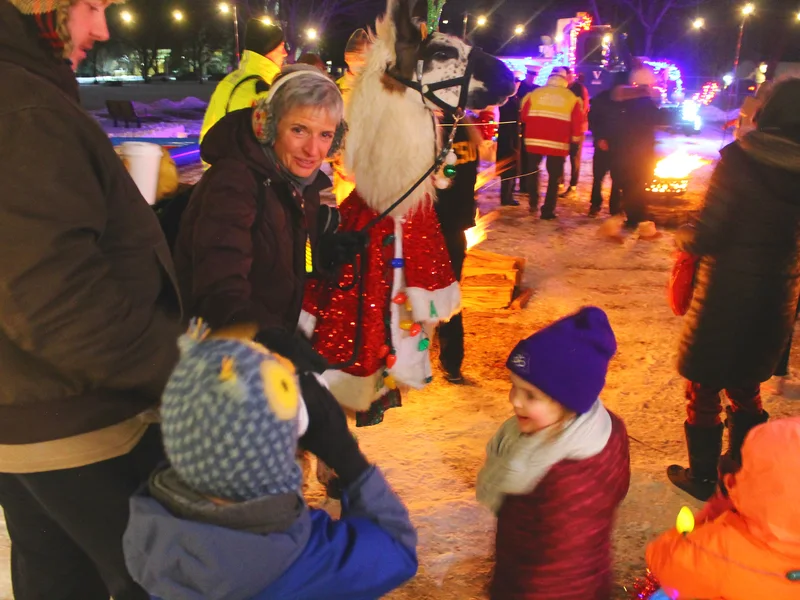Families in winter coats under string lights at Light Up Victoria