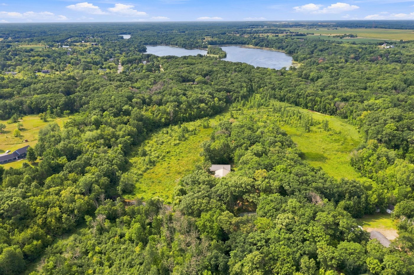 Aerial of the five wooded acres with the lake beyond